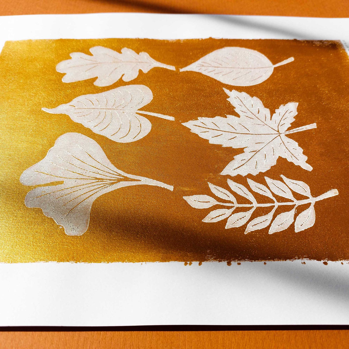 gold acrylic white oil ink autumn wall art linocut print white leaves foraged rustic fall new home gift original artwork thanksgiving table hallway decor grandmother hostess gift one of a kind linogravure botanical office lino cottagecore nature lover leaf farmhouse thank you bedroom printmaking handprinted farm minimalist self sister mom mother hostess new apartment godmother wife woman living room kitchen handmade dining for Her Thankful Gratitude Entryway Dorm Warm Earth Tones Seasonal